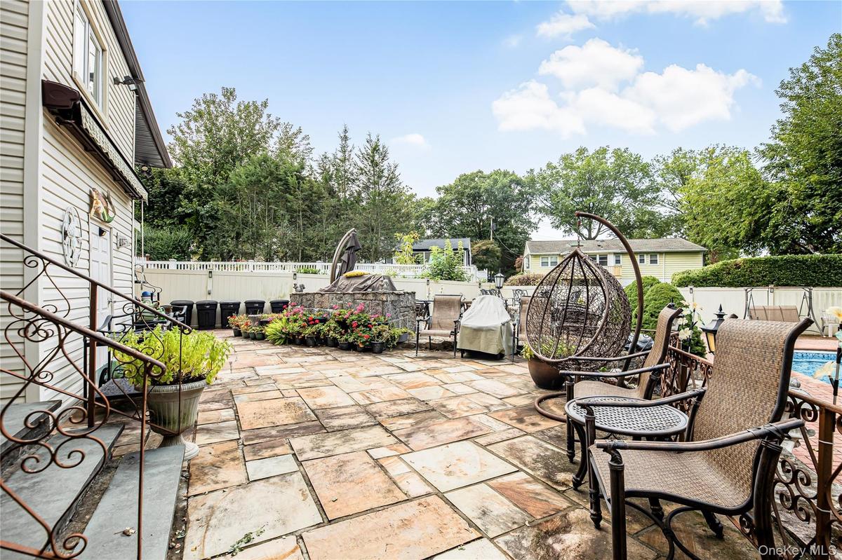 Expansive stone patio featuring a stone-faced raised planter and white privacy fencing