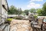 Expansive stone patio featuring a stone-faced raised planter and white privacy fencing