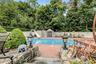 Swimming pool with a water slide, surrounded by a brick paver patio and privacy fencing