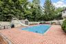 Swimming pool with a water slide, surrounded by a brick paver patio and privacy fencing