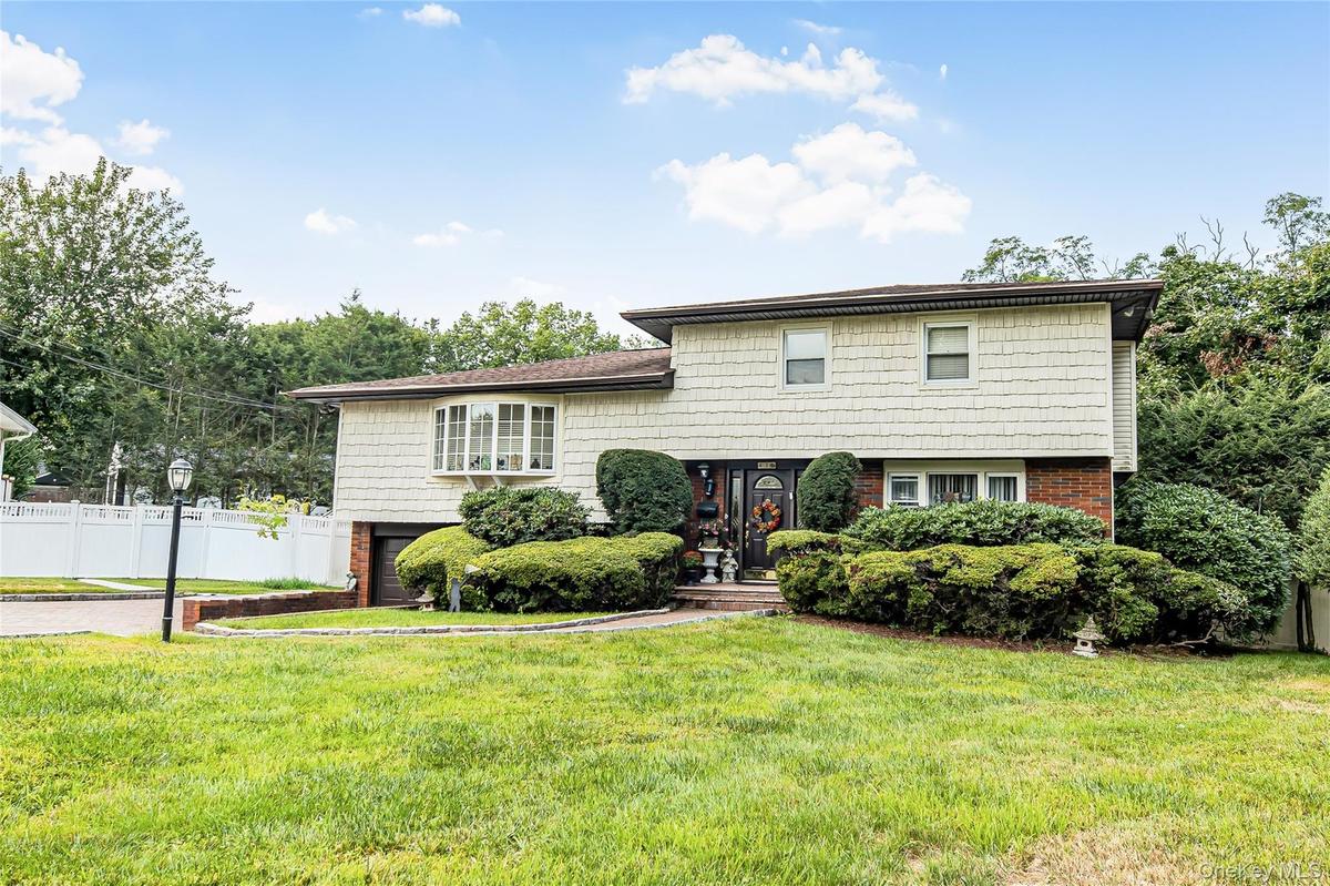 Split-level residence featuring a bay window, brick foundation, and shingle siding