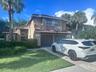 Terracotta-style roof, stucco exterior, arched entry, mature landscaping, and an attached two-car garage