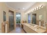 The en-suite bathroom offers separate vanity areas, each with their own private toilet, and a central walk-in shower with dual framless glass doors