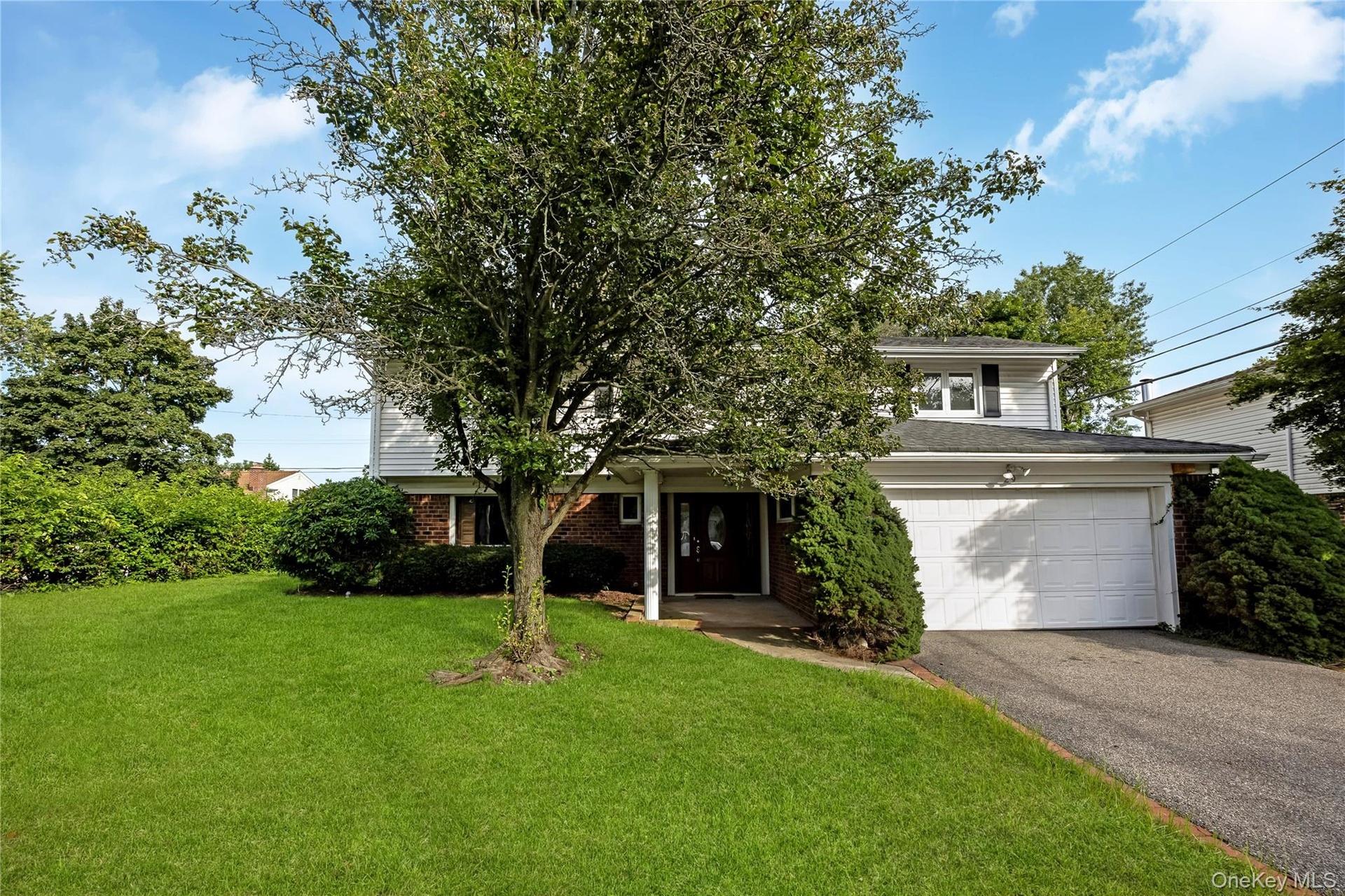 WELCOME HOME to 29 Randy Lane! Three-story residence featuring a front lawn, mature tree, attached two-car garage, and a covered entry. Grass enhanced
