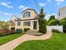 Two-story residence with a light-colored exterior and dark shutters
