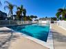 Expansive outdoor swimming pool with a surrounding white picket fence, concrete decking, and tropical landscaping