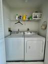 Built-in laundry closet with louvered bifold doors, wire shelving, and overhead lighting