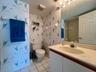Integrated vanity with a single basin sink, wall-mounted mirror, and overhead vanity lighting