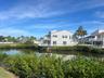 Waterfront property featuring multiple balconies, a white exterior, and mature palm trees