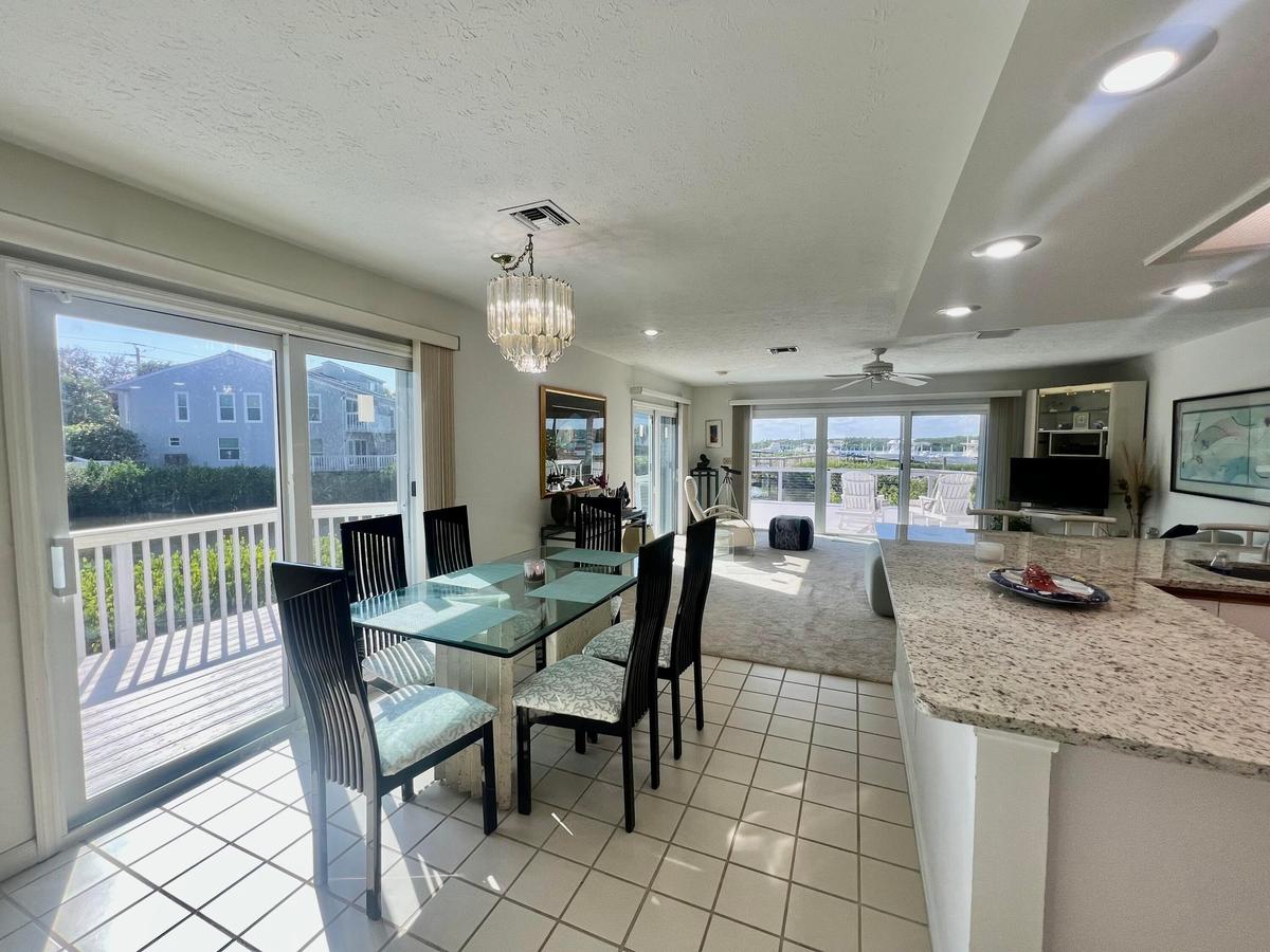 White tile flooring, sliding glass doors, a decorative chandelier, recessed lighting, and a granite countertop