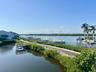 Waterfront setting with multiple boat slips, a wooden boardwalk, and established tropical landscaping