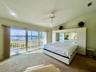 Sliding glass doors opening to a waterfront, vaulted ceiling, recessed lighting, and a ceiling fan