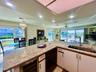 Large L-shaped kitchen island with integrated sink, under-cabinet wine refrigerator, and light-toned countertops