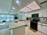 Kitchen featuring white cabinetry with brushed nickel hardware, light-colored granite countertops, a tiled backsplash, and recessed lighting