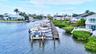 Waterfront property featuring a private boat dock, lush landscaping, multiple balconies, and a canal setting