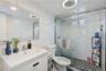 Modern full bathroom featuring a glass-enclosed walk-in shower, contemporary tilework, sleek vanity, and stylish lighting. 2nd Floor Unit.