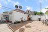 Detached white brick garage with a roll-up door, paved patio, and white lattice fencing