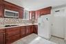 Updated kitchen featuring rich wood cabinetry, tile backsplash, ample counter space, and plenty of storage. 1st Floor.