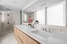 Spacious ensuite bath featuring dual sinks, oversized mirror, and glass shower — luxury meets functionality.