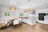 Contemporary open-concept kitchen with white cabinetry, quartz countertops, stainless-steel appliances, and designer lighting.