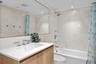Minimalist guest bath with modern tile, frameless shower, and elegant lighting.