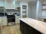 Kitchen featuring a central island with a light-toned countertop, stainless steel range, white cabinetry, and wood-finish flooring