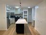 Kitchen featuring wood-finish flooring, stainless steel appliances, a center island with a white countertop, recessed lighting, and white cabinetry
