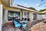 Exterior patio with brick-finish pavers, sliding glass doors, white-framed windows, and a terracotta tile roof
