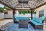 Paved patio featuring a built-in gazebo with a chandelier and privacy curtains