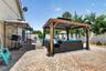 Brick paver patio featuring a covered gazebo with integrated lighting, a swimming pool, and a privacy fence