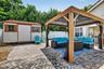 Brick paver patio featuring a covered gazebo, storage shed, and white privacy fencing