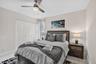 Light wood-finish flooring, a ceiling fan with integrated lighting, and white bi-fold closet doors