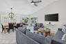 Vaulted ceilings with a ceiling fan, white tile flooring, sliding glass doors to the exterior, and a dining area with a chandelier