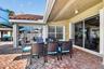 Brick paver patio with a covered dining area, multiple sliding glass doors, and a tile roof