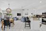 Open-concept living and kitchen area featuring light-filled spaces with large glass sliding doors, white cabinetry with granite countertops, stainless