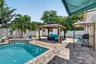 Brick paver patio with an in-ground swimming pool, tile-finish spa spillway, and a permanent gazebo structure