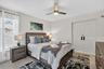 Light wood-finish flooring, two-panel bifold doors, window with blinds, and a ceiling fan with integrated lighting