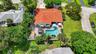 Aerial view of a Spanish Colonial residence featuring a distinctive barrel tile roof, resort-style saltwater pool with surrounding hardscape and loung