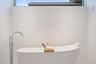 Modern spa-inspired soaking tub with curved silhouette and seamless white finish, paired with a contemporary floor-mounted freestanding tub filler fea