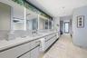 Dual vanity with integrated sinks, white countertops, built-in medicine cabinets with integrated lighting, wood-finish flooring, and a large horizonta