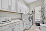 Large Laundry room with GE front loader washer and dryer with steam and lots of storage.