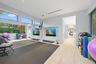 Expansive fitness space featuring light wood-finish flooring, full-height wall mirrors, and large windows with transom panels