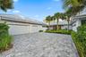 Paver driveway, mature palm trees, contemporary exterior, metal roof, and integrated landscaping