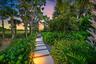 Paver pathway with integrated lighting, surrounded by diverse plantings including palm trees and lush greenery