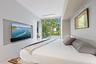Recessed wall-mounted television with soundbar, full-height sliding glass doors, and a built-in headboard with integrated lighting