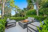 Paved patio with a built-in fire pit, surrounded by lush landscaping and mature trees