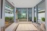 Light-filled sunroom with floor-to-ceiling glass panels, horizontal louvre shutters, and light wood-finish flooring