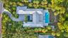 Expansive property featuring a winding paver driveway, lush landscaping, two distinct swimming pools, and a private outdoor lounge area