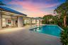 Expansive outdoor living area featuring a large swimming pool, covered patio, and lush tropical landscaping