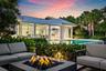 Modern residence with clean-lined architecture and metal roof, featuring expansive glass sliding doors and a covered porch